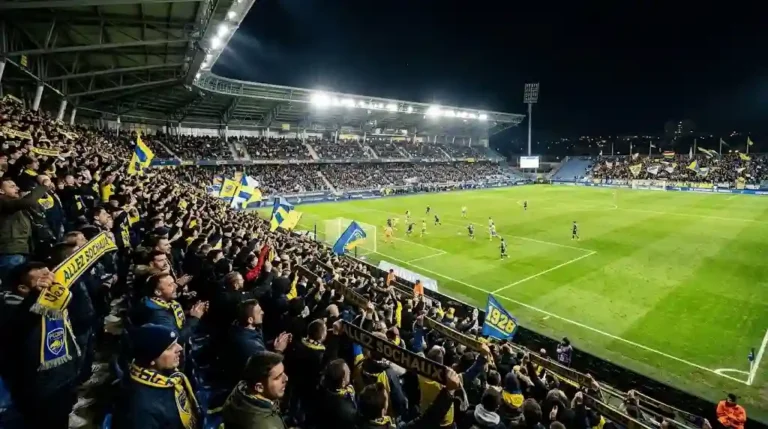 Ambiance exceptionnelle dans les tribunes lors des matchs de ligue 2 dans un stade illuminé de nuit.